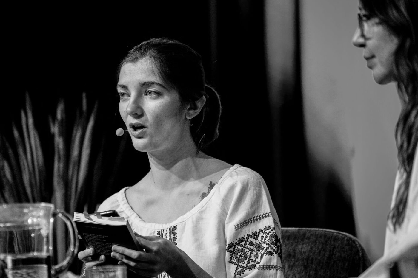 Ung kvinne leser fra en bok på scenen, svart-hvitt